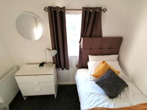 泰恩河畔纽卡斯尔Milton House - Entire 3Bed House FREE WIFI & 4 FREE PARKING Spaces Serviced Accommodation Newcastle UK的一间小卧室,配有一张床和镜子