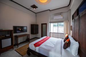 清迈Chirin Home ฌิรินทร์โฮม的一间卧室配有一张床、一台电视和一张四柱床。