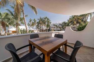 拉巴斯Hotel & Suites El Moro的棕榈树阳台的桌椅
