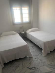 桑卢卡尔-德巴拉梅达Ronda的白色客房的两张床,设有两扇窗户