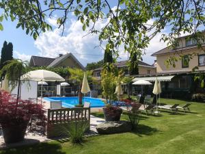 韦尔特湖畔克伦彭多夫Ferienanlage Seehof的庭院内的游泳池,配有椅子和遮阳伞