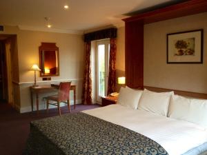 拉夫堡Quorn Country Hotel的酒店客房设有一张大床和一张桌子。