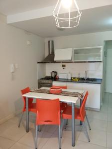 玛德琳港Monoambiente Libertad 345的厨房配有白色的桌子和红色的椅子