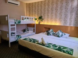 马六甲Grandeur Hotel And Spa的客房设有两张床和一张双层床。