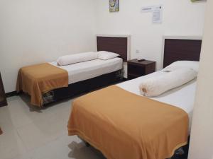 BiromaruFidelia Homestay Palu Mitra RedDoorz的配有两张床垫的酒店客房内的两张床