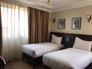 内罗毕Hemak Suites的酒店客房设有两张床和窗户。