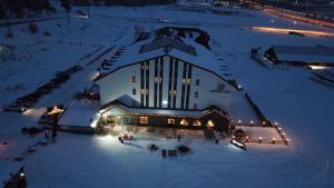 SarıkamısSarikamis Habitat Hotel的一座大建筑,晚上有灯光,雪中