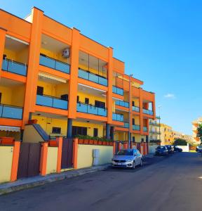 加利波利Case Vacanza IonianTravel Gallipoli的一座橙色的建筑,前面有停车位