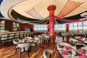 阿勒皮Ramada by Wyndham Alleppey的一间带桌椅和大型天花板的餐厅