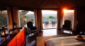 赫卢赫卢韦桑达游猎山林小屋的一间卧室配有一张床,阳台配有椅子