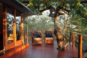 赫卢赫卢韦桑达游猎山林小屋的木门廊,带两把椅子和一棵树