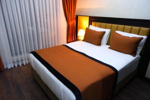 伯萨Dimen Hotel的一间卧室配有一张带橙色枕头的大床
