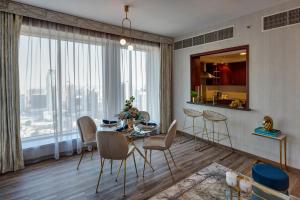 迪拜Durrani Homes - Designer 2BR Apt with stunning Burj khalifa and Fountain View的一间带桌椅和大窗户的用餐室
