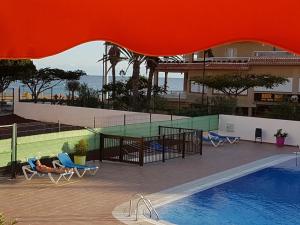 洛斯克里斯蒂亚诺斯PLAYA LAS VISTAS LOFT的享有带椅子的游泳池和大楼的景色