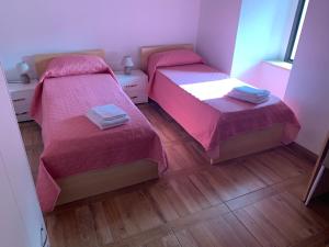 科森扎B&B L’antico Rudere的客房 - 带2张带粉红色床罩的床和木地板