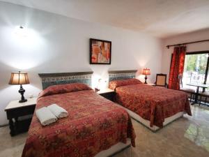 梅里达多尔巴酒店的酒店客房,配有两张带红色床单的床