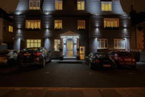 伦敦Croft Court Hotel的两辆汽车晚上停在大楼前