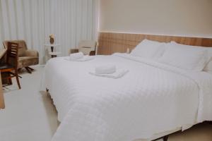 圣安娜-利弗拉门图Confort Fronteira Hotel的卧室内的一张大白色床,配有椅子