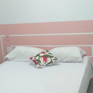 卡拉瓜塔图巴Pousada NOVA Catavento的一张带两个枕头的白色床和粉红色床头板