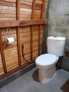 巴图卡拉Coconut Tree Cottages的浴室设有白色卫生间和木墙