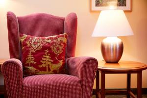 格明德Hotel & Restaurant Stern的一张带枕头的椅子和一张桌子上的灯