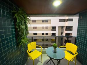 马塞约Apartamento na Ponta Verde Maceió Facilities的阳台配有黄色椅子和桌子,大楼