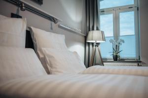 格吕克斯塔特Hotel & Restaurant Christian IV的一间卧室配有一张带白色床单的床和一扇窗户。