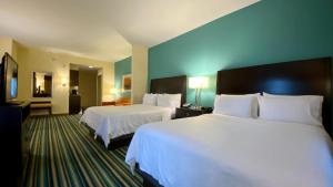 奥兰多奥兰多东智选假日套房酒店的酒店客房,配有两张带白色床单的床
