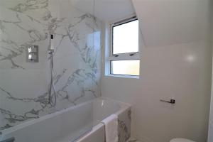 伦弗鲁Jess View的白色的浴室设有浴缸和大理石墙。
