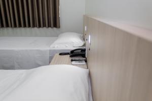 伊达贾伊Hotel Vitoria - Itajaí的客房设有两张床和一张桌子及两部电话