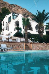 圣夫拉维亚Villa del Golfo Urio with swimming pool shared by the two apartments的游泳池前棕榈树的房子