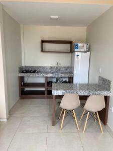 戈亚斯州上帕莱索Delú Residences的厨房配有柜台、冰箱和2把椅子