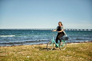 尼堡斯托贝尔特西纳图尔酒店及会议中心的一位妇女在海滩上骑着自行车