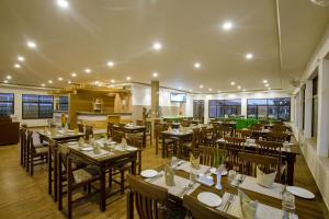 索拉哈Vision Safari Pvt Ltd的餐厅设有木桌、椅子和窗户。