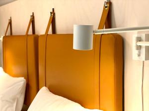 马尔默时光酒店的一张宽大的橙色床头板,床头上方有灯