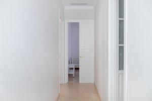 塞维利亚Hispalis Casa Palacio Apartment的一条带白色墙壁和开放式门的走廊