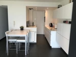 尼乌波特Marjolaine Zeezicht - Nieuwpoort-bad met GRATIS garagebox的厨房配有白色橱柜和白色的桌椅