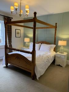 AshwellThree Tuns Ashwell的卧室配有带白色床单的木制天蓬床