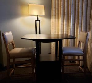 坎卢普斯Coast Kamloops Hotel & Conference Centre的餐桌,配有两把椅子和一盏灯