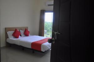 那格浦尔Hotel Relax Inn的一间卧室配有一张带红色枕头的床和一扇窗户