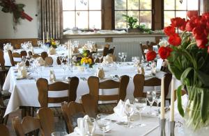 Mainhardt兰德加斯托夫索纳尔酒店的一间设有白色桌椅和红色鲜花的餐厅