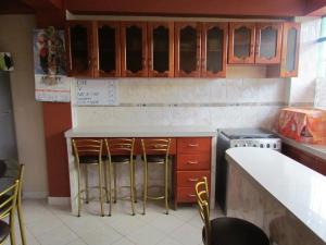 库斯科可库瓦赛酒店的厨房配有木制橱柜和酒吧凳子