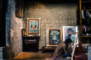 香格里拉阿若康巴南索达庄园 的坐在带绘画的房间椅子上的人