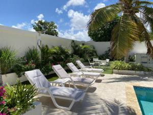 棕榈滩Yoyita Suites Aruba的一组白色躺椅和一个游泳池