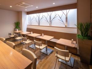 富士市Super Hotel JR Fujiekimae Kinenkan的餐厅设有桌椅和大窗户。