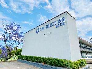 悉尼The Select Inn Ryde的白色的建筑,旁边标有标志