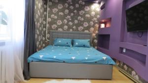 波洛茨克Апартаменты Art House в центре Полоцка的一间卧室配有一张带蓝色床单和紫色墙壁的床。
