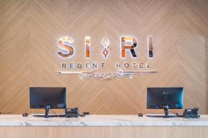 那空拍侬府Siri regent Hotel的一张桌子,上面有两个显示器,位于度假村的标志前