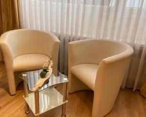 赫费尔霍夫威斯曼维明图哥公寓酒店的两把椅子坐在玻璃桌旁,带花瓶
