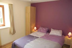 塞尔方丹Le Clos des Haies, Silenrieux的一间卧室配有一张紫色墙壁的床和两盏灯。